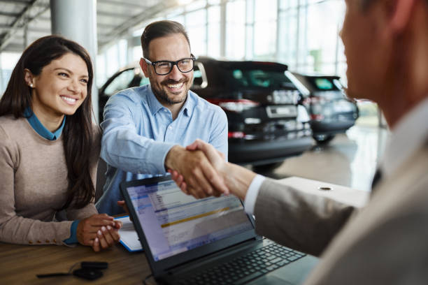 Happy couple came to an agreement with car salesperson in a showroom. stock photo