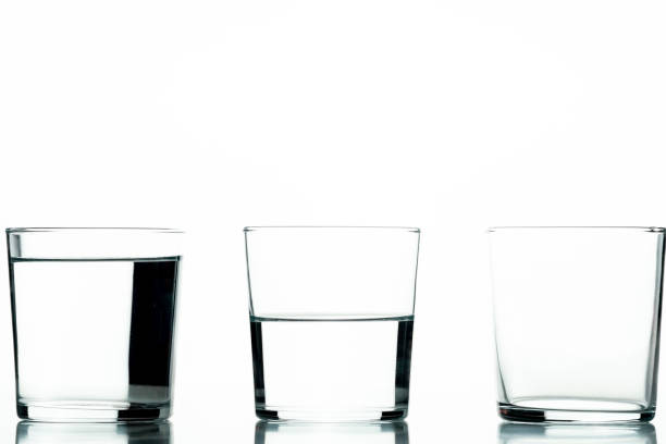 istock Three crystal glasses, one full of liquid, one half-full and one empty - concept of quantity and capacity 1426478266