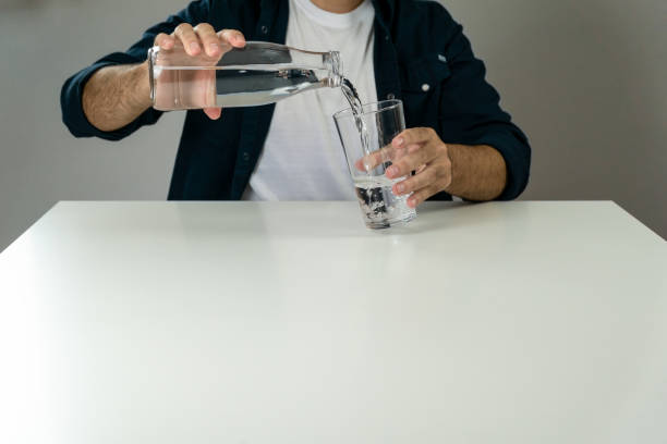 istock Unrecognizable man pouring water into a glass to hydrate himself - hydration and wellness concept 1426478276
