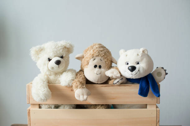 soft children's animal toys in a wooden box - speelgoedbeest stockfoto's en -beelden