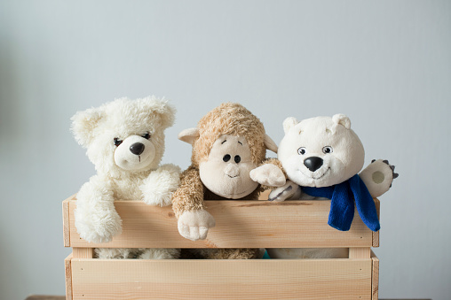 Smiling white, light brown and dark brown teddy bears sitting on table at pink wall background. Pastel color. Togetherness and friendship concept. Front view. Closeup.
