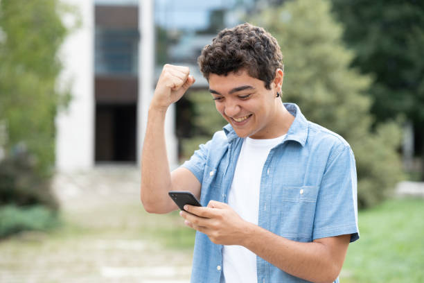 istock Hispanic boy celebrating good results on phone 1426480365