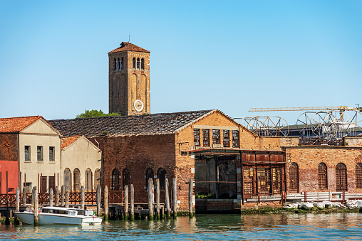 Murano island, bell tower of the Cathedral, Basilica of saints Maria and Donato, VII century, and abandoned ancient glass factories. Venetian lagoon, Venice, UNESCO world heritage site, Veneto, Italy, Europe. This Venetian island is famous for the production of artistic glass.
