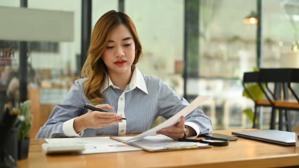 istock Young female accountant using calculator and examining the numerical data on financial document. 1426482173