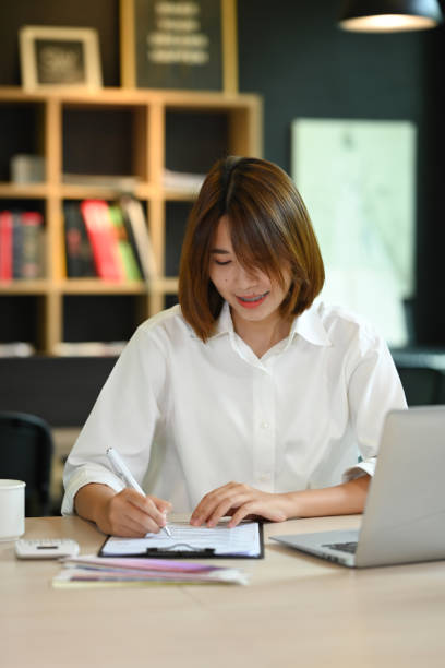 istock Portrait of successful entrepreneur using laptop computer and doing some paperwork at her office. 1426482319