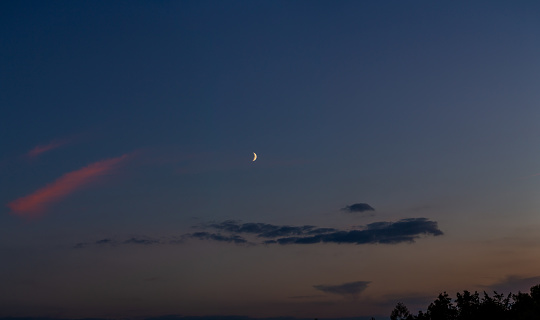 Blue and pink colored sky with the waxing moon decorating it