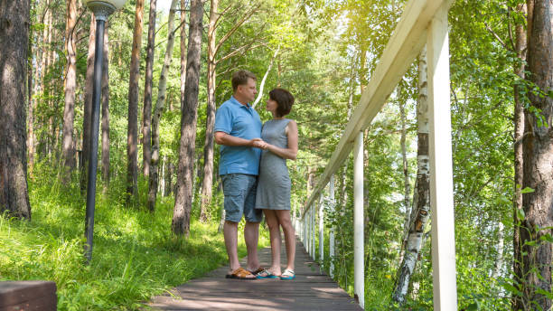 um casal adulto apaixonado, um homem e uma mulher, estão em uma ponte no parque - tall short men women - fotografias e filmes do acervo