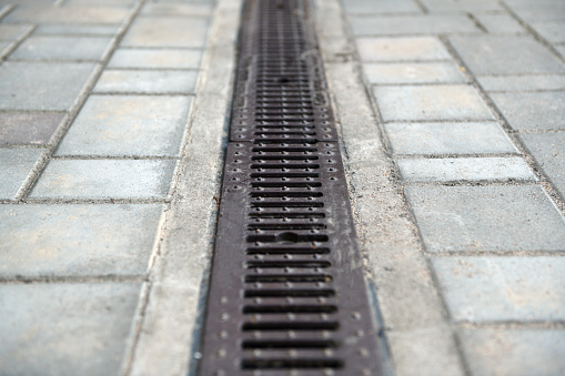 Drainage system with stainless steel composite grating between paving slabs.