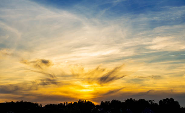 Beautiful summer sunset over the horizon with sunlight, clouds and blue sky