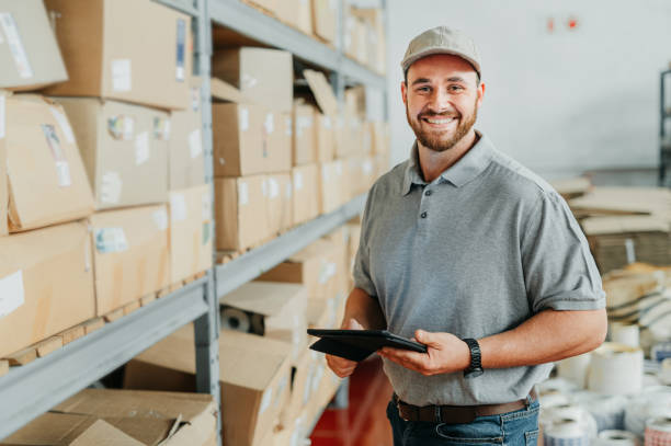 istock Ecommerce, logistics and supply chain with a man courier working with a tablet in a distribution warehouse, factory or plant. Delivery, stock and shipping cargo in the export and import industry 1426490320