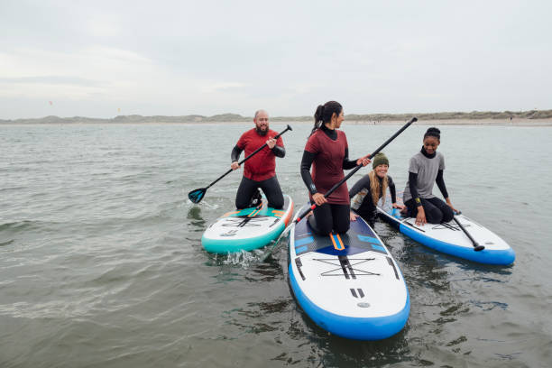 friends learning paddle boarding - surfing sport extreme sports success imagens e fotografias de stock