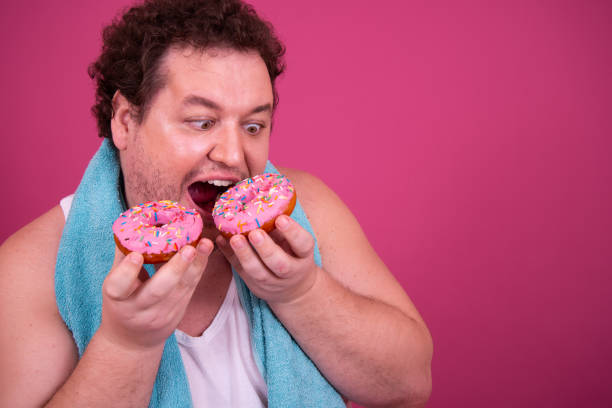 istock Breakfast and sports. Funny fat man eats donuts. 1426501667