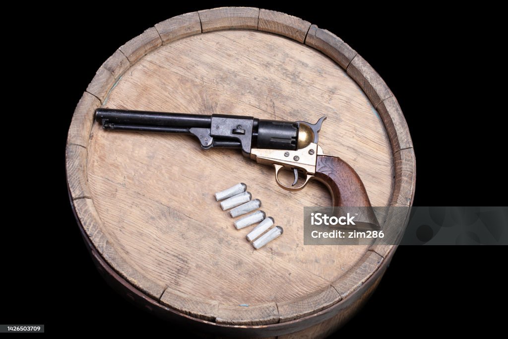 Old West Gun - Percussion Army Revolver Old West Gun - Percussion Army Revolver and paper cartridges with lead ball as projectiles on wooden barrel College American Football Stock Photo