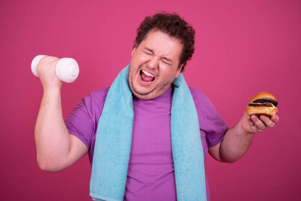 istock Diet and fast food. Funny fat man eats a hamburger. 1426505580
