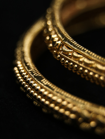 vintage golden bangles with ornate details carved captured in a closeup macro photo isolated in a black background
