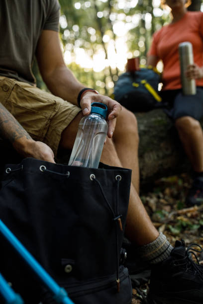 istock Man unpacking water bottle from a backpack when taking a break from a hike 1426512636