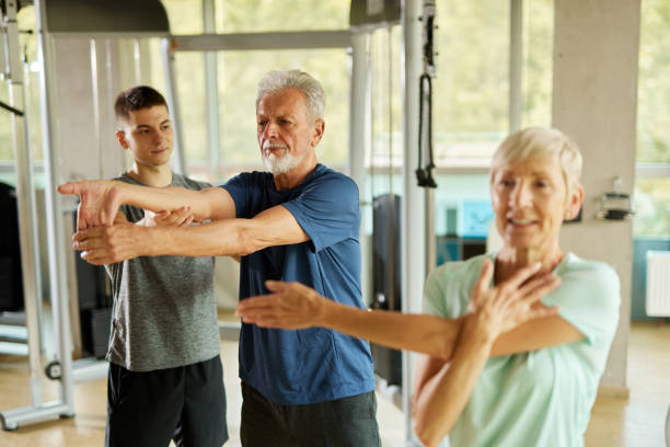 istock Senior couple doing stretching exercises with personal trainer at the gym 1426513980