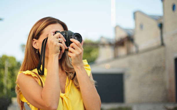 istock Beautiful woman taking pictures with her camera while exploring a city 1426516288