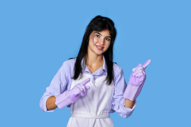 girl in yellow rubber gloves pointing fingers aside at copyspace beautiful caucasian girl in violet rubber gloves pointing fingers aside at copyspace isolated on blue background. cleaning sign human hand pointing manual worker stock pictures, royalty-free photos & images