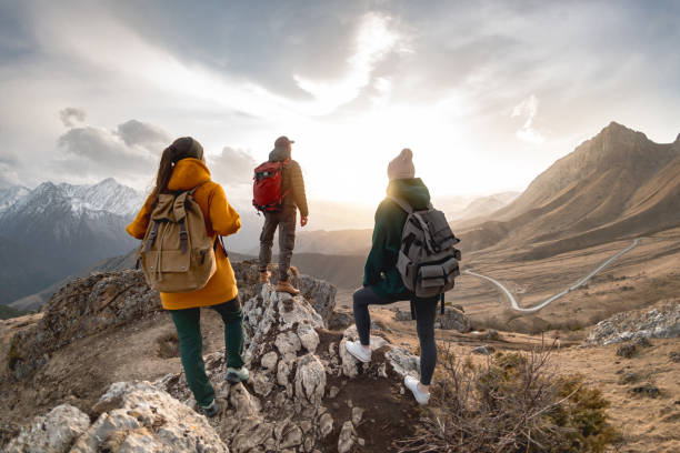 gruppe von touristen wandert bei sonnenuntergang in den bergen - people traveling journey group of people hiking stock-fotos und bilder