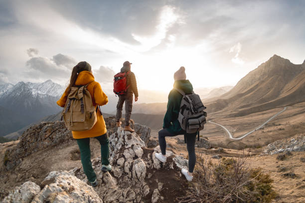 gruppe von touristen wandert bei sonnenuntergang in den bergen - moving up looking men people stock-fotos und bilder