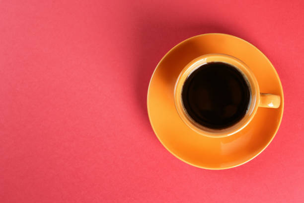 istock Coffee in cup on red background, top view. Space for text 1426542199