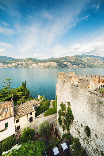 Malcesine, Italy - September 3, 2022: View of Lake Garda from the Castello Scaligero - Malcesine, Italy. Malcesine is a comune (municipality) on the eastern shore of Lake Garda in the Province of Verona in the Italian region Veneto. It is nestled between Lake Garda and the slopes of Monte Baldo; immediately to its north lies Trentino-Alto Adige. Malcesine's most prominent landmark is the Castello Scaligero, which has 13th-century fortifications and an older medieval tower in white natural stone; it is named for the della Scala family of Verona who ruled the region in the 13th and 14th centuries, and has the characteristic swallow-tail Ghibelline merlon crenallations.