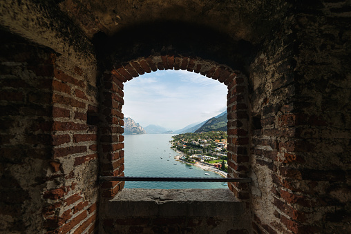 Malcesine, Italy - September 3, 2022: Malcesine beach and Lake Garda seen from Castello Scaligero tower. Malcesine's most prominent landmark is the Castello Scaligero, which has 13th-century fortifications and an older medieval tower in white natural stone; it is named for the della Scala family of Verona who ruled the region in the 13th and 14th centuries.