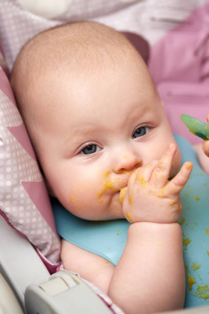 istock baby girl eating with spoon in kitchen 1426542982