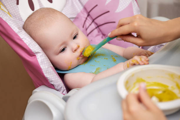 istock baby girl eating with spoon in kitchen 1426543016