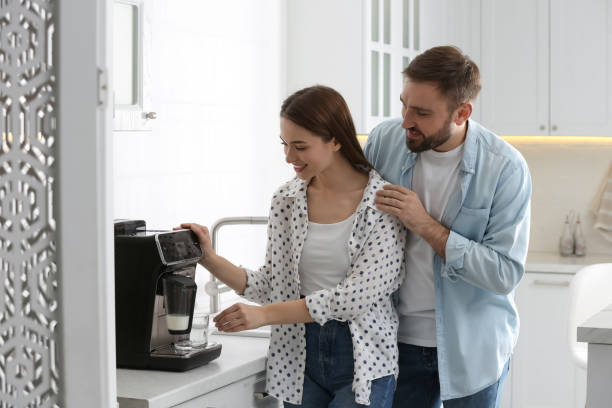 istock Happy couple preparing fresh aromatic coffee with modern machine in kitchen 1426543302