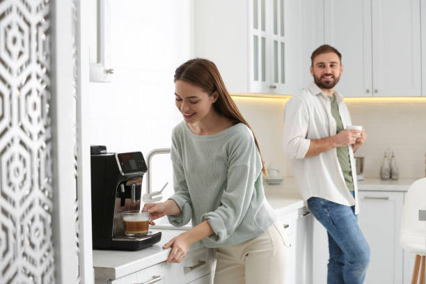 istock Happy couple preparing fresh aromatic coffee with modern machine in kitchen 1426543304