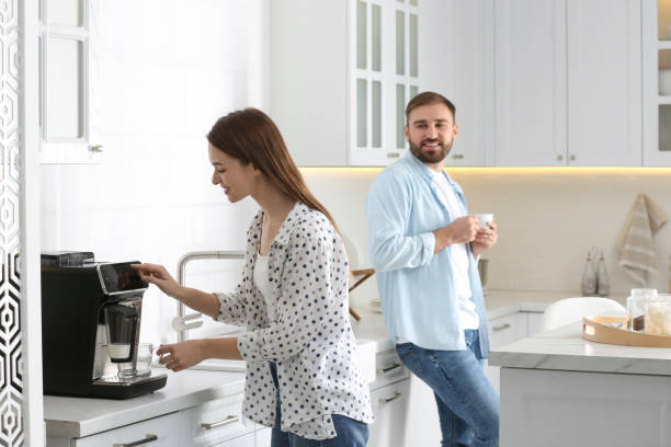 istock Beautiful young woman and her boyfriend using modern coffee machine in kitchen 1426543305