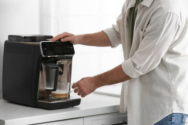 istock Young man preparing fresh aromatic coffee with modern machine in kitchen, closeup 1426543334