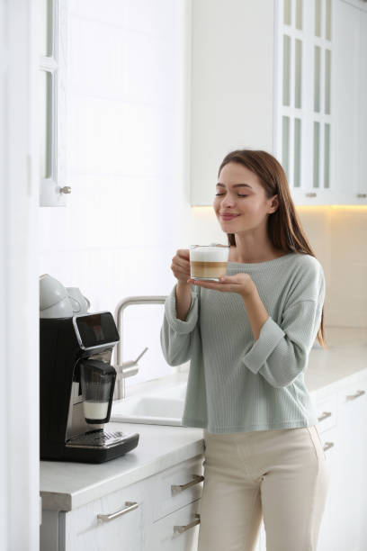 istock Young woman enjoying fresh aromatic coffee near modern machine in kitchen 1426543352