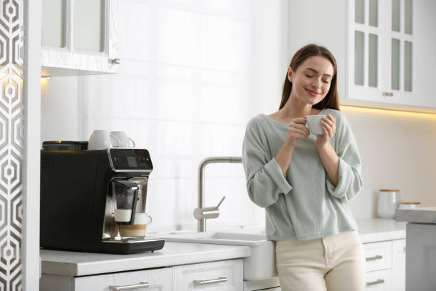 istock Young woman enjoying fresh aromatic coffee near modern machine in kitchen 1426543356