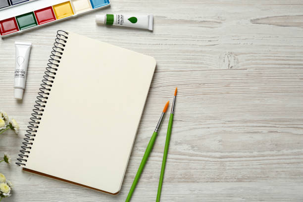istock Flat lay composition with blank sketchbook on white wooden table. Space for text 1426543389