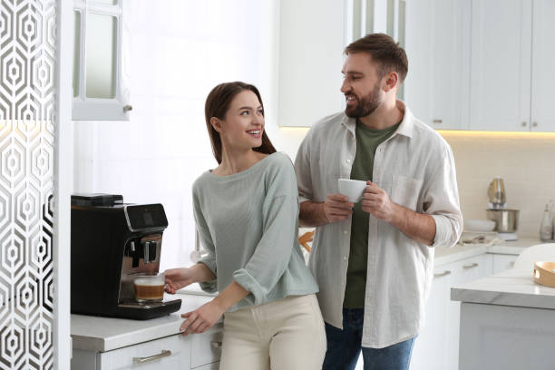 istock Happy couple preparing fresh aromatic coffee with modern machine in kitchen 1426543395