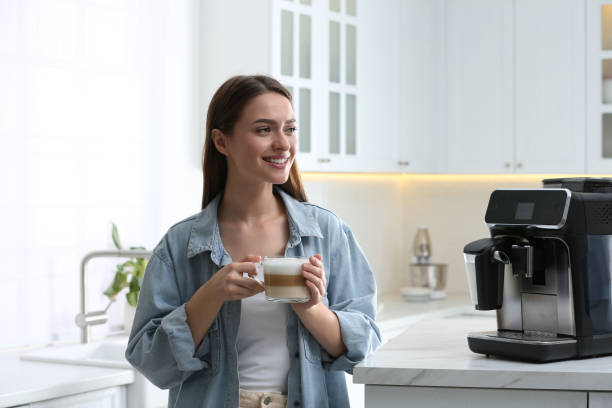 istock Young woman enjoying fresh aromatic coffee near modern machine in kitchen 1426543476