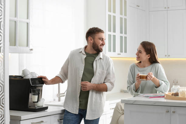 istock Happy couple preparing fresh aromatic coffee with modern machine in kitchen 1426543530