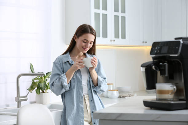 istock Young woman enjoying fresh aromatic coffee near modern machine in kitchen 1426544092