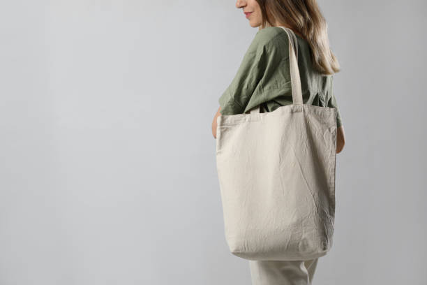 istock Young woman with blank eco friendly bag on light background, closeup. Space for text 1426544121