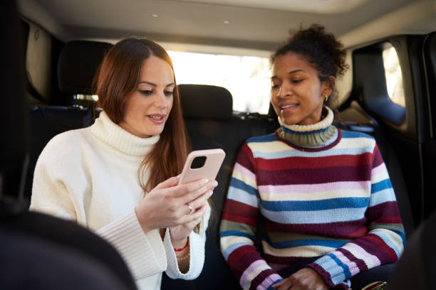 istock Two friends share a smartphone in a car. 1426544192