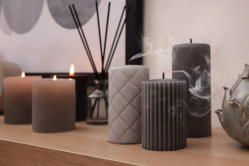 Blown out candles and air freshener on wooden shelf indoors