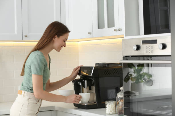 Young woman preparing fresh aromatic coffee with modern machine in kitchen Young woman preparing fresh aromatic coffee with modern machine in kitchen coffee maker stock pictures, royalty-free photos & images