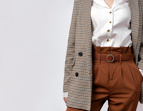 Business concept. A woman in a tweed jacket, brown trousers with a belt. holds his hand in his pants pocket with space for text. Empty space under the inscription. Photo for your design