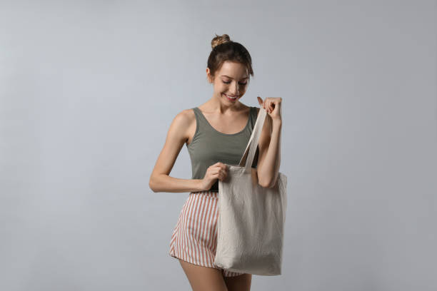 istock Happy young woman with blank eco friendly bag on light background 1426544646