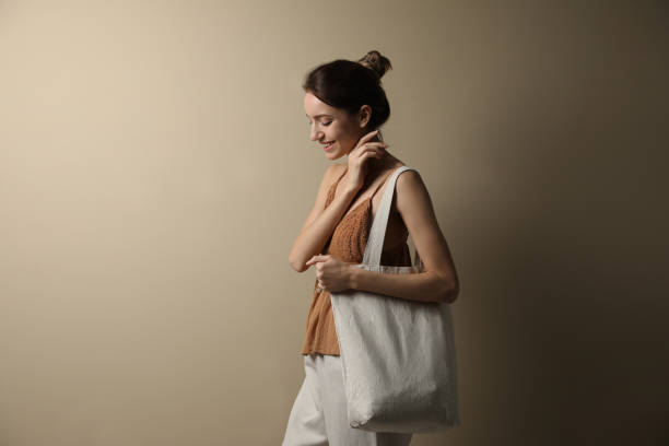 istock Happy young woman with blank eco friendly bag against beige background 1426544708