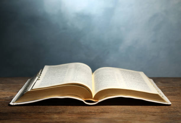 istock Open Bible on wooden table against color background. Christian religious book 1426548574