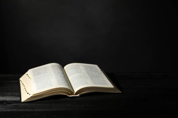 istock Open Bible on black wooden table, space for text. Christian religious book 1426548575